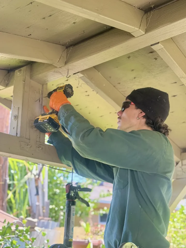 Localized Termite Treatment vs. Tenting in California: What Your WDO Report Really Means 1 Treebark technician drilling patio beams during termite treatment, orange gloves and company patches