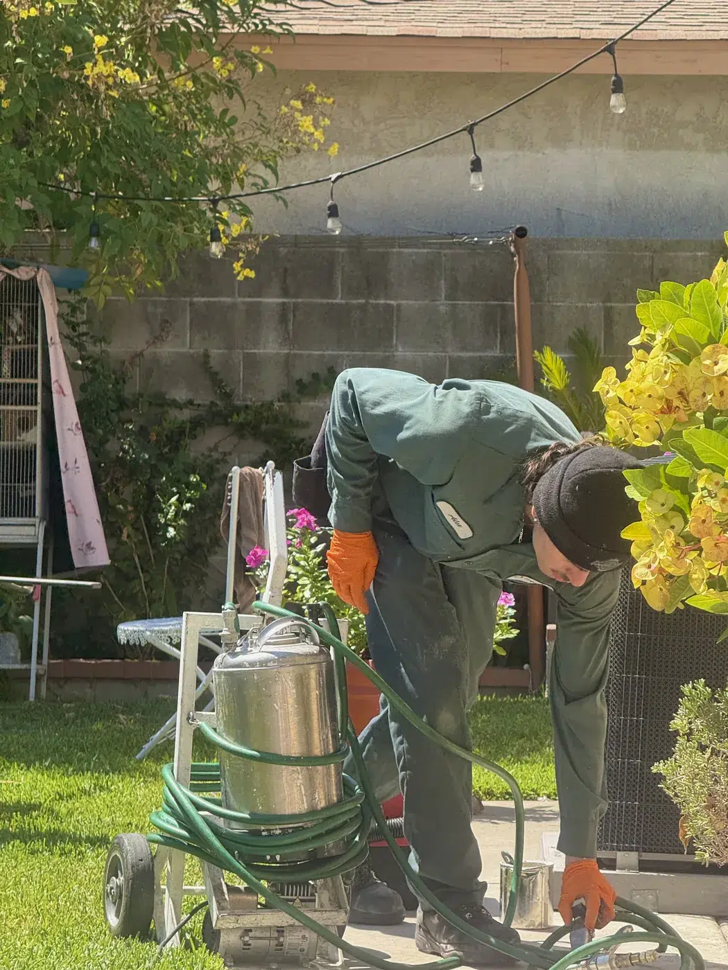 Irvine Treebark technician treating a backyard with a sprayer tank